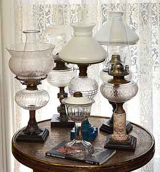 Kerosene table lamps displayed. Photo of six early kerosene table lamps with burners and shades.